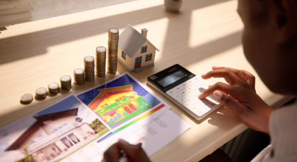 Person mit Taschenrechner und aufgetürmten Geld