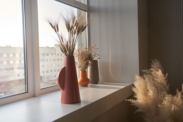 Nahaufnahme eines modernen beigen Backsteinhauses mit großen Dreiecksfenstern und einem steilen Satteldach vor einem strahlend blauen Himmel.